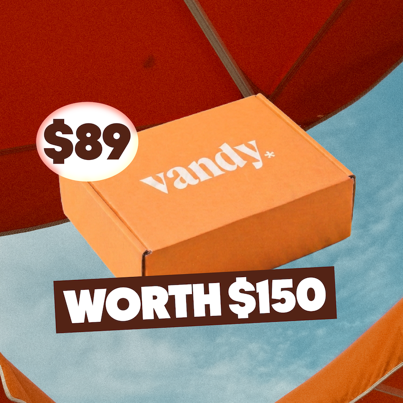 An orange Vandy brand subscription box is shown floating against a blue sky background, framed by red patio umbrellas. White text overlays read 'BOX 01', '$89', 'WORTH $150', and '2 PIECES'.